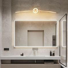 a bathroom with a sink, mirror and lights on the wall above it's counter