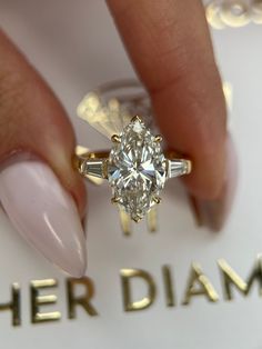 a woman's hand holding a diamond ring on top of a sign that says her diamonds