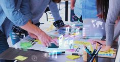 several people standing around a table with papers and pencils