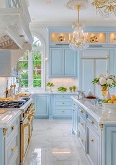 a large kitchen with blue cabinets and white marble counter tops, gold trimmings and chandeliers