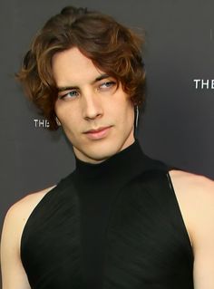 a young man in a black dress posing for the camera