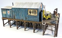 a toy truck is parked next to a wooden structure with shacks on the top