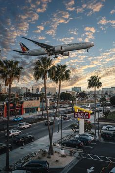 an airplane is flying over a fast food restaurant with palm trees in the foreground