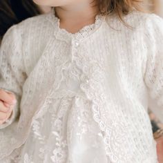 Handmade in the USA The Penelope Knit Sweater is a wonderful addition to your Penelope outfit. Made of 100% knit in ivory. Venice lace trim with floral embroidered lace and pearl style buttons. The bonnet also features Venice lace trim all the way around the edge. Soft elastic stretches for a comfortable fit for baby. Ivory silk ribbon ties are a beautiful extra touch. So special and pretty, perfect to keep her warm and it will look gorgeous with any outfit. 100% knit acrylic in ivory Venice lac Long Sleeve Lace Top For Fall Wedding, White Lace Long Sleeve, White Cardigan For Spring Wedding, Fall White Lace Top, Fall Wedding Lace Top, White Lace Cardigan For Fall, Elegant Fitted Cardigan With Lace Trim, Cream Lace Top With Lace Trim For Fall, White Long Sleeve Cardigan For Wedding