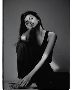 a black and white photo of a woman sitting on the floor