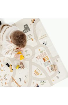 a baby playing with toys on a playmat in the shape of a city map