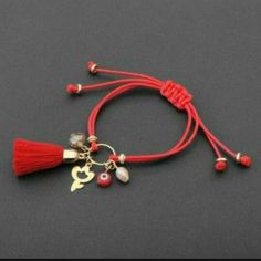 a red cord bracelet with two charms and a tassel hanging from it's end