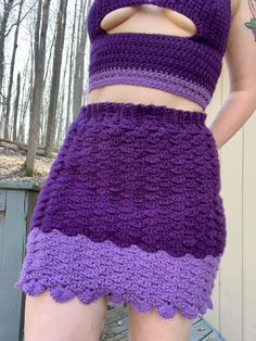 a close up of a person wearing a purple and black crochet skirt with cut outs