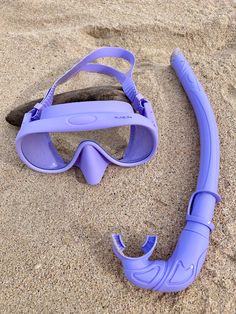 a pair of purple goggles laying in the sand