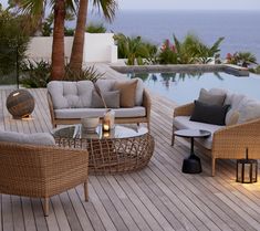 an outdoor living area with wicker furniture and palm trees next to the swimming pool