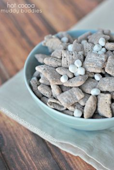 a blue bowl filled with white and gray dog treats on top of a wooden table