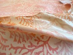 an orange and white floral print fabric on a bed sheet with a tag in the middle