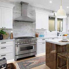 a large kitchen with white cabinets and marble counter tops, an island in the middle