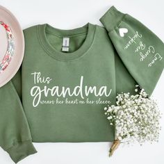 a green sweatshirt with the words, this grandma is heart on her sleeve next to a pink plate and flowers