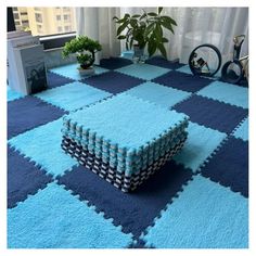 a blue and black rug with squares on the floor in front of a large window