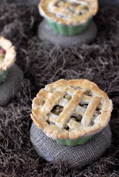 four small pies sitting on top of a pile of brown grass next to each other