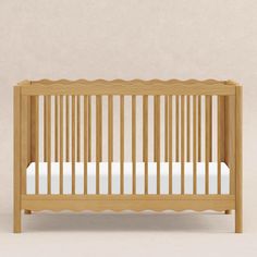 a small wooden crib with white sheets on the bottom and sides, in front of a beige wall