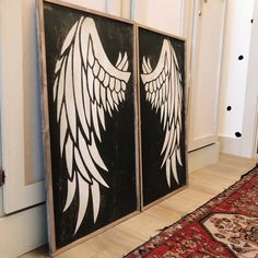 two black and white paintings with wings on them in front of a red area rug