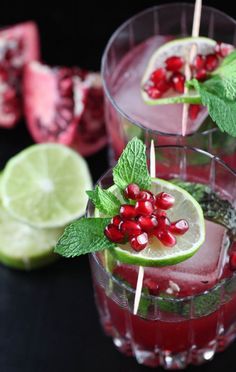 two glasses filled with pomegranate, lime and mint garnishes