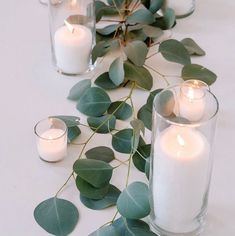 candles and eucalyptus leaves are arranged on the table