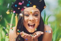 a woman wearing a graduation cap and throwing confetti on her face