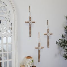 three wooden crosses are hanging on the wall next to a vase with flowers in it