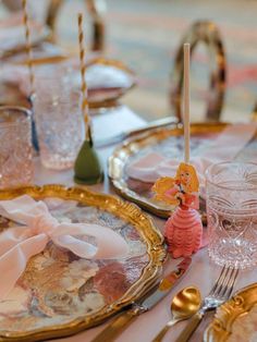 the table is set with plates, silverware and pink napkins for an elegant dinner