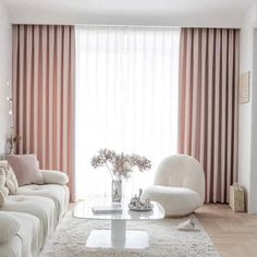 a living room with white furniture and pink curtains