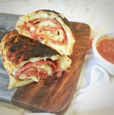 a sandwich cut in half sitting on top of a cutting board next to a bowl of ketchup