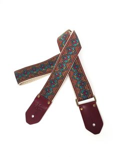 a pair of brown leather guitar straps with colorful designs on them, sitting on a white surface