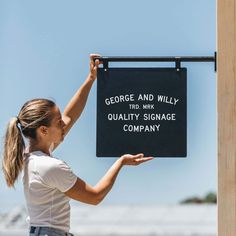 a woman holding up a sign that says george and willy quality signage company on it