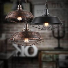 three pendant lights hanging from the ceiling in an industrial style room with exposed brick walls