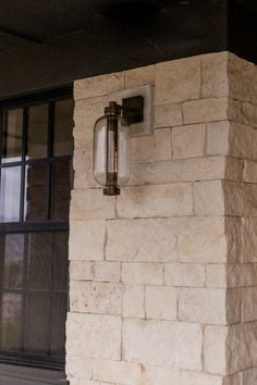 a clock on the side of a brick building next to a window with glass panes