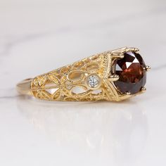 This gorgeous ring features a rich red spinel paired with a romantic, vintage style setting! The round cut spinel center has a deep and highly saturated red hue! The 14k yellow gold setting is studded with diamonds and beautifully embellished with curling filgree. The effect is classic, graceful, and sweetly feminine.The 2.56ct spinel is vibrantly saturated with very rich color. It is eye clean, luminous, and dimensional, displaying a beautiful play of light and color. The accent diamonds are br Red Spinel, Vintage Cocktail Ring, Diamond Cocktail Ring, Diamond Cocktail Rings, Yellow Gold Setting, North South, Gold Filigree, Ring Vintage, Cocktail Ring