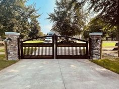 a driveway gate with stone pillars and gates