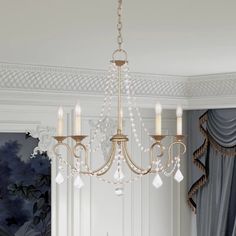 a chandelier hanging from the ceiling in a room with blue curtains and white walls