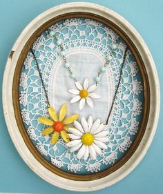 two daisies are sitting on a doily with necklaces hanging from the side