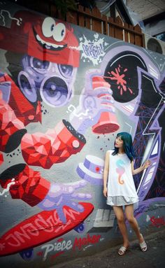 a woman standing next to a wall covered in graffiti