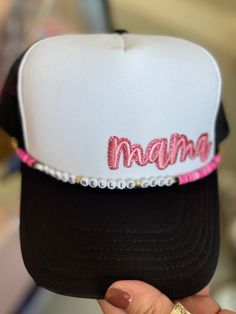 a person holding up a hat with the word mama written on it in pink and black