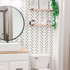 a white toilet sitting under a bathroom mirror next to a wooden counter top and shelf