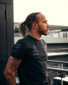 a man with dreadlocks standing in front of a building looking off into the distance