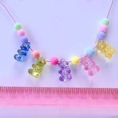 the beaded bear necklace is next to a measuring tape and a pink ruler with two bears on it