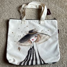 a white bag with a woman's face painted on the front and side, sitting on carpet