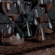 an assortment of sandglasses sitting on top of a wooden table next to each other