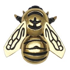 a gold and black bee brooch sitting on top of a white surface