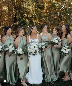 a group of women standing next to each other holding bouquets in their hands and smiling