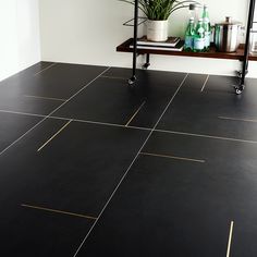 a black tile floor with gold lines on it and a potted plant in the corner