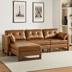 a brown leather couch sitting on top of a wooden floor next to a white rug