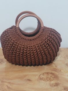 a brown crocheted bag sitting on top of a wooden table