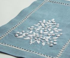 a blue napkin with white embroidered flowers on it